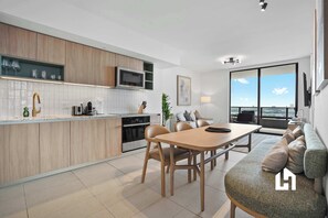 A modern kitchen with a dining area, a sofa, and a large window with a view. - Bay-View High-Rise: Private Balcony, Pool & Gym (Miami)
