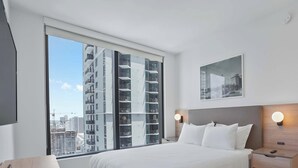 A hotel room with a large window, a bed, a nightstand, and a wall-mounted light. - Bay-View High-Rise: Private Balcony, Pool & Gym (Miami)