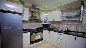 A kitchen with white cabinets, a stainless steel refrigerator, a stove, and a microwave. - Cairo Taj Dokki Families Tower Hotel (Giza)