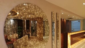 A lobby with a large circular mirror, a reception desk, and a seating area with patterned chairs. - Cairo Taj Dokki Families Tower Hotel (Giza)