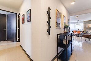A modern interior with a hallway leading to a dining area, featuring a black metal shelf with decorative items and framed artwork on the walls. - Artful Roma Norte Stay Near Museums & Cafés (Cuauhtemoc)