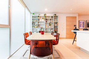 Un espace repas moderne avec une table ronde, des chaises orange et un meuble blanc.