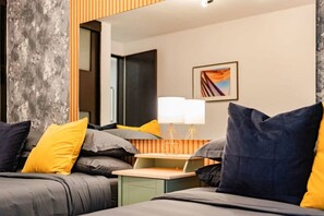 Une chambre d’hôtel moderne, équipée d’un lit, d’une table de chevet et d’une lampe.