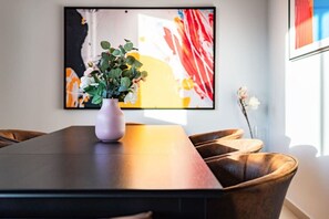 A dining area with a long table, a vase with flowers, and a large abstract painting on the wall. - Penthouse in Roma Norte with City Skyline View (Mexico City)