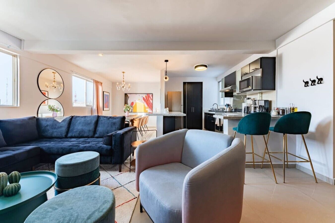 Un salon moderne avec un canapé d’angle, une table basse ronde et un coin repas doté d’un bar.