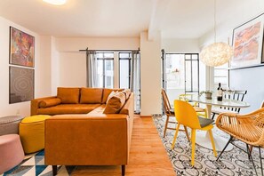 A modern living room with a sofa, a dining table with chairs, and a large window with curtains. - Vibrant Condo in Roma Norte Walk to Museums & Eats (Mexico City)
