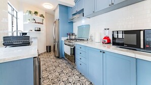 A modern kitchen with blue cabinets, a stainless steel refrigerator, a red blender, and a patterned floor. - Vibrant Condo in Roma Norte Walk to Museums & Eats (Mexico City)