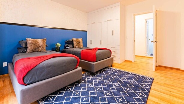 A bedroom with two beds, a wardrobe, and a patterned rug. - Vibrant Condo in Roma Norte Walk to Museums & Eats (Mexico City)