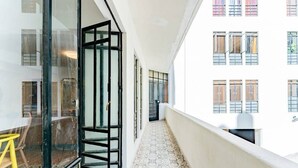 A narrow corridor with patterned flooring, a glass door, and a view of a building with multiple windows. - Vibrant Condo in Roma Norte Walk to Museums & Eats (Mexico City)