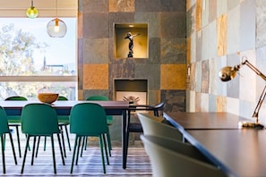Un comedor moderno con pared de piedra, chimenea y vistas al exterior.