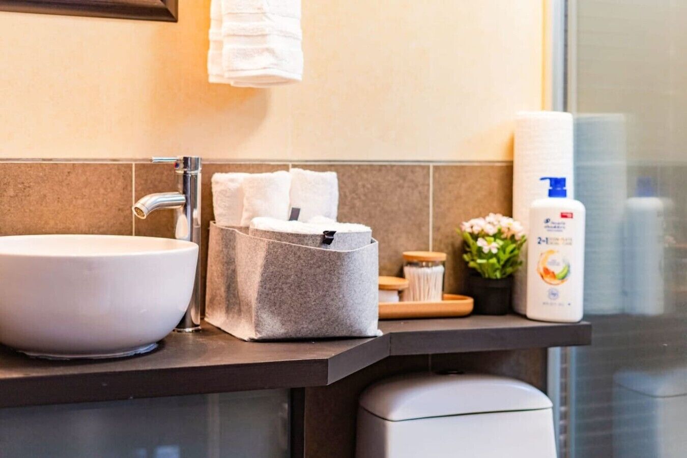 Une salle de bain avec un lavabo blanc, un distributeur de serviettes et des articles de toilette posés sur le comptoir.