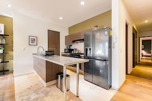 A modern kitchen with stainless steel appliances, a granite countertop, and a wooden cabinet. - Roma Norte Condo: Balcony, Parking & City Views (Mexico City)