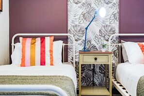 A hotel room with two beds, a nightstand with a lamp, and a floral-patterned curtain. - Roma Norte Condo with City Views & Workspace (Mexico City)