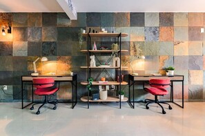A modern office space with two desks, red chairs, and a central shelving unit. - Roma Norte Condo with City Views & Workspace (Mexico City)