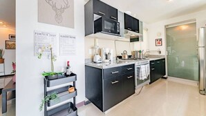 Uma cozinha moderna com armários pretos, forno embutido, micro-ondas e cafeteira.