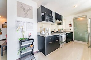 Eine moderne Küche mit schwarzen Schränken, einem eingebauten Backofen, einer Mikrowelle und einer Kaffeemaschine.