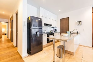 Eine moderne Küche mit einem schwarzen Kühlschrank, weißen Schränken, einer Edelstahlspüle und einer Arbeitsplatte aus Granit.