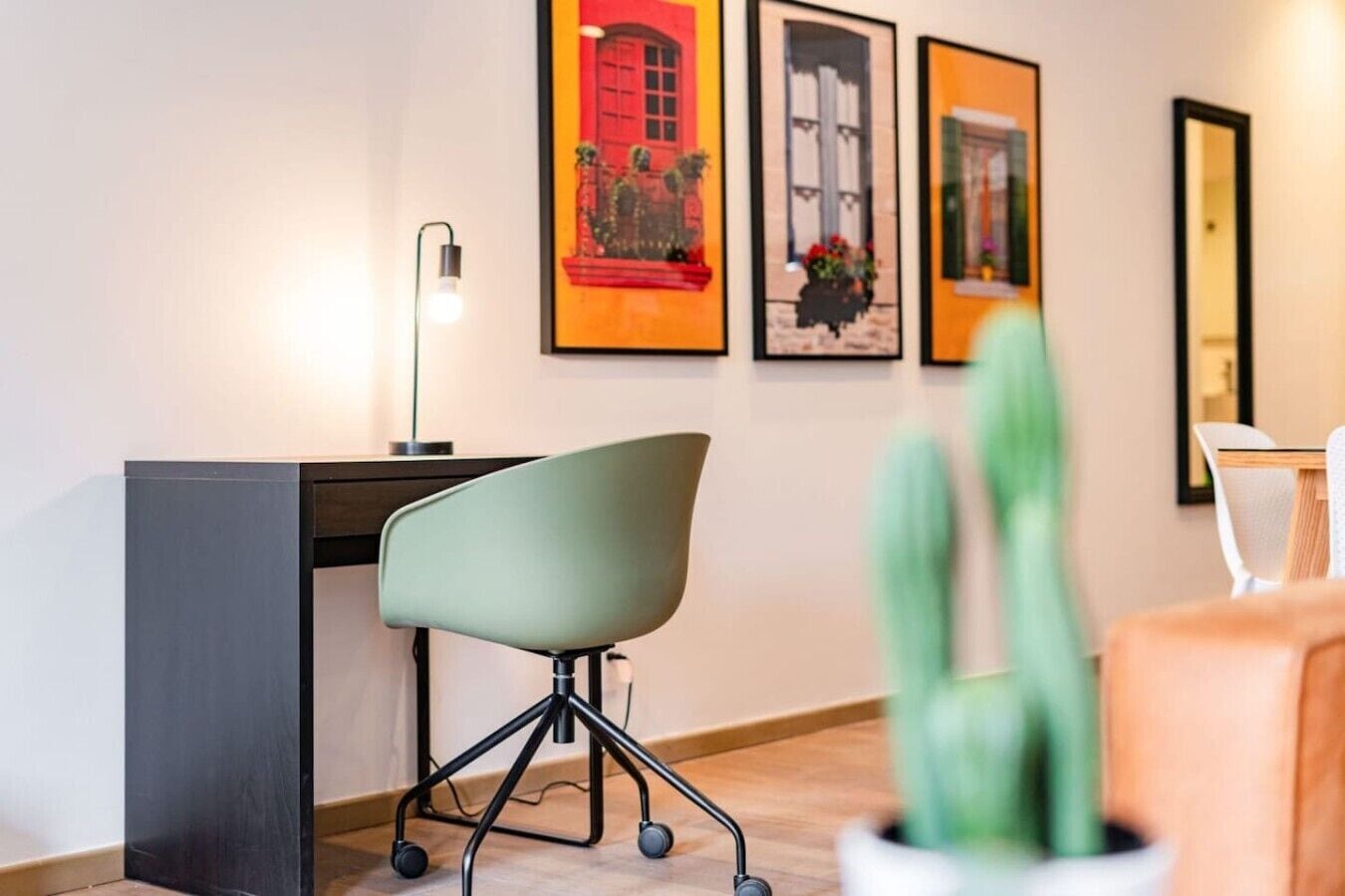 A modern office space with a desk, office chair, and framed artwork on the wall.