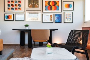 Ein modernes Wohnzimmer mit Esstisch, zwei Stühlen, einem Couchtisch und einer Wand mit gerahmten abstrakten Kunstwerken.