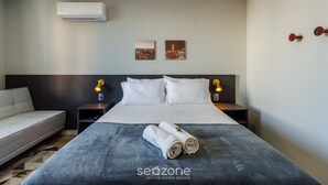 Ein Hotelzimmer mit einem Bett, einem Sofa, zwei Wandleuchten und zwei gerahmten Bildern.