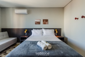Ein Hotelzimmer mit einem Bett, einem Sofa, zwei Wandleuchten und zwei gerahmten Bildern.