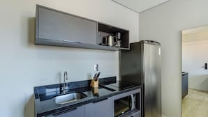 Ett modernt kök med ett kylskåp i rostfritt stål, en inbyggd ugn och en diskho med blandare.