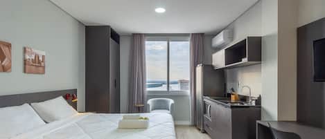 A hotel room with a bed, a desk, a chair, a window with a view, and a TV.