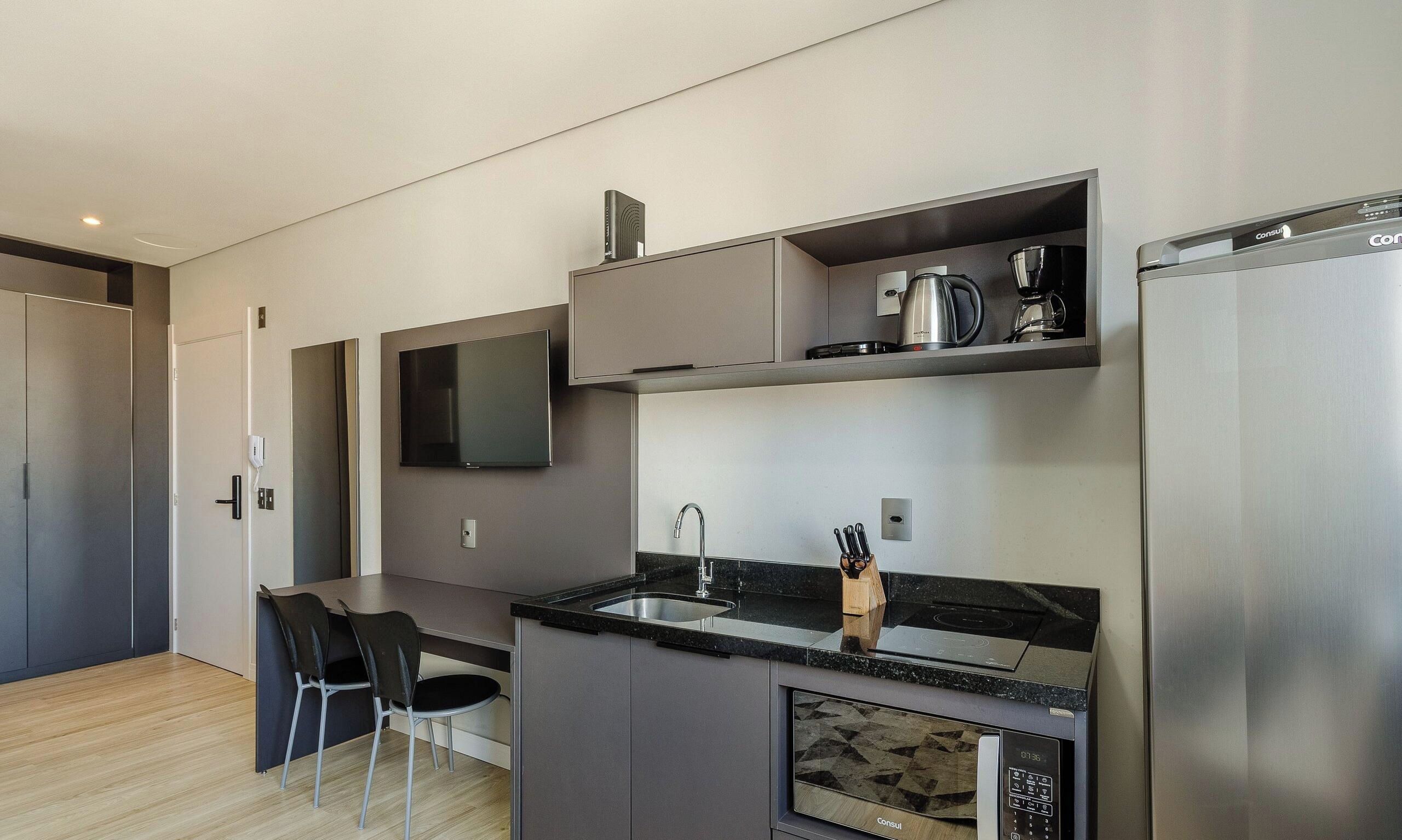 A modern kitchen with a built-in microwave, coffee maker, and a sink.