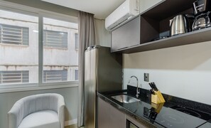 A compact kitchen with a built-in stove, a sink, and a window with blinds. - Studio w/ Pool nr Santa Casa Tco0210 (Porto Alegre)