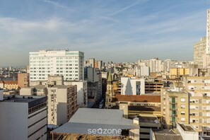 A cityscape with a variety of buildings, including a prominent white building with a flat roof and a smaller building with a green roof in the foreground. - Apt in H. Center in Bldg. w/ Pool Tco1115 (Porto Alegre)