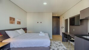 Ein modernes Hotelzimmer mit Bett, Schreibtisch, Stuhl, Fernseher und einer Tür zu einem Badezimmer.