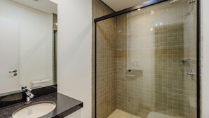 Uma casa de banho moderna com chuveiro envidraçado, lavatório com bancada preta e sanita branca.