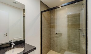 Ein modernes Badezimmer mit einer Glaskabine für die Dusche, einem Waschbecken mit schwarzer Arbeitsplatte und einer weißen Toilette.