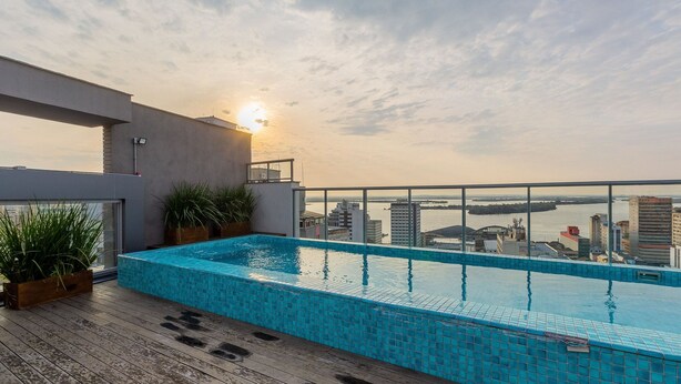 Piscina infinita no terraço com vista para a cidade, plantas em vasos e design arquitetônico moderno.