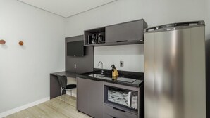 Uma cozinha compacta com geladeira embutida, cafeteira e escorredor de facas.