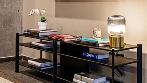 A modern living room with a large flat-screen TV mounted on the wall, a black entertainment unit with books and decorative items, and a small table with a lamp. - Stylish 1BR • Gym & Workspace • Near Reforma (Mexico City)