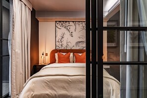 A modern bedroom with a large bed, a nightstand with a lamp, and a wall with a floral pattern. - Stylish 1BR • Gym & Workspace • Near Reforma (Mexico City)