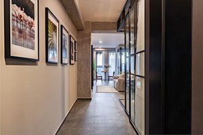 A hallway with framed artwork on the walls, leading to a seating area with a table and chairs. - Stylish 1BR • Gym & Workspace • Near Reforma (Mexico City)