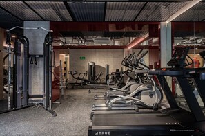 Une salle de sport équipée de tapis de course, d’appareils de musculation et d’un support à squats.