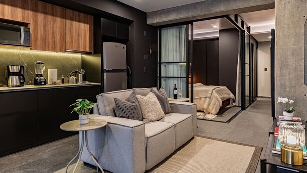 A modern hotel room with a kitchenette, a sofa, a small table, and a bed. - Stylish 1BR • Gym & Workspace • Near Reforma (Mexico City)