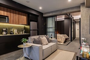 A modern hotel room with a kitchenette, a sofa, a small table, and a bed. - Stylish 1BR • Gym & Workspace • Near Reforma (Mexico City)