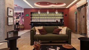 A modern lobby with a green sofa, a bar area, and a patterned wall. - Stay Together: 3 Apts, Rooftop & Gym Near Reforma (Mexico City)