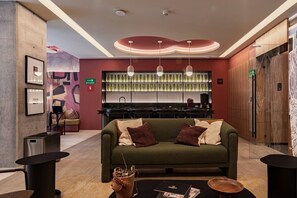 A modern lobby with a green sofa, a bar area, and a patterned wall. - Stay Together: 3 Apts, Rooftop & Gym Near Reforma (Mexico City)