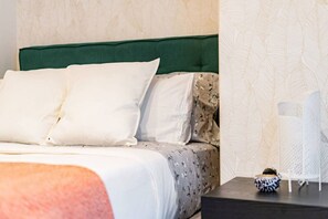 A neatly made bed with white and patterned bedding, a green upholstered headboard, and a nightstand with a decorative item. - Roma Norte | Steps From Restaurants & Nightlife (Mexico City)