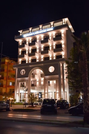 Un hotel de varios pisos con una entrada destacada que presenta arcos grandes y un balcón en el piso superior.