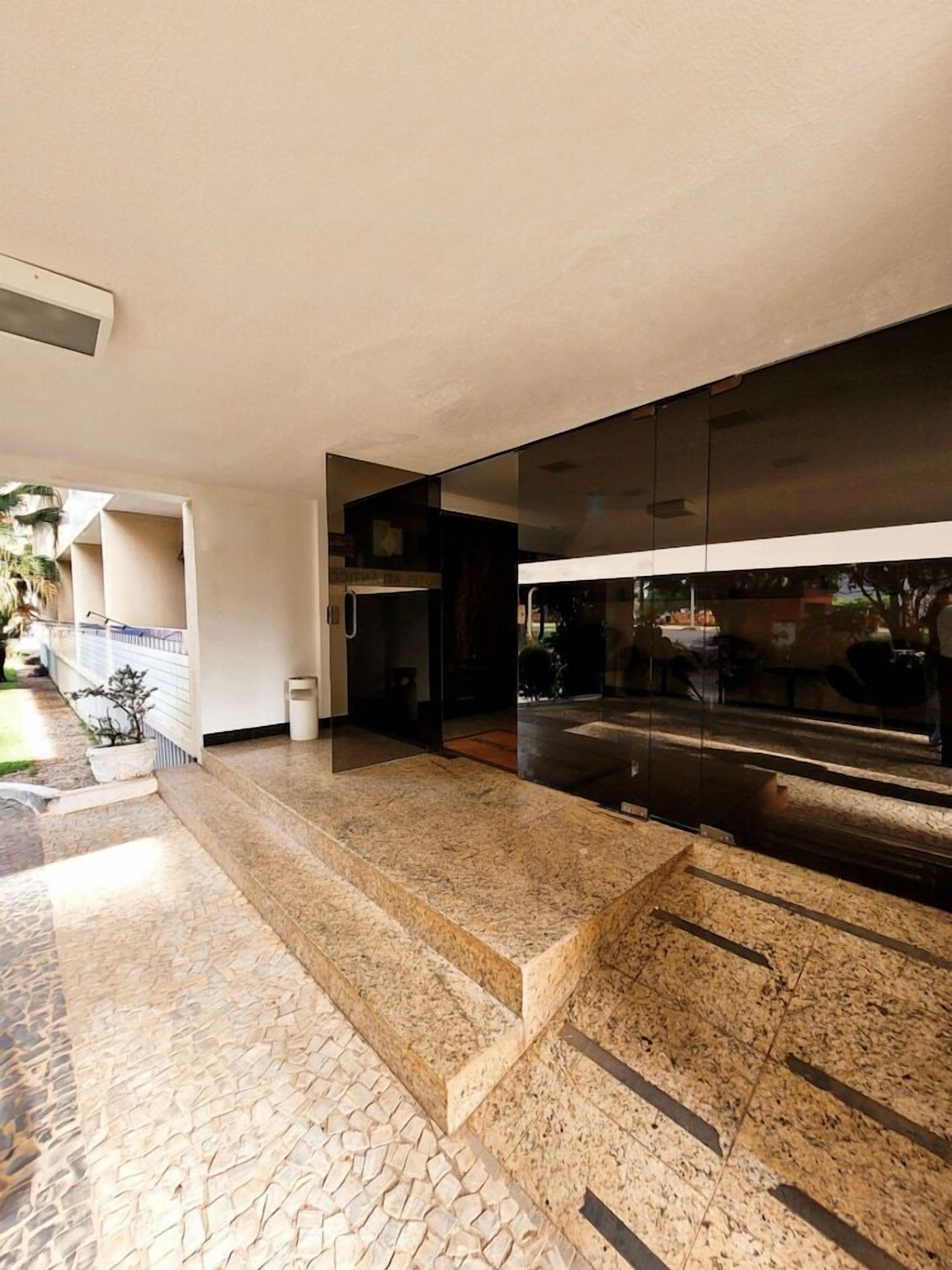 Um hall moderno com entrada de vidro, uma lixeira e piso revestido de azulejos.