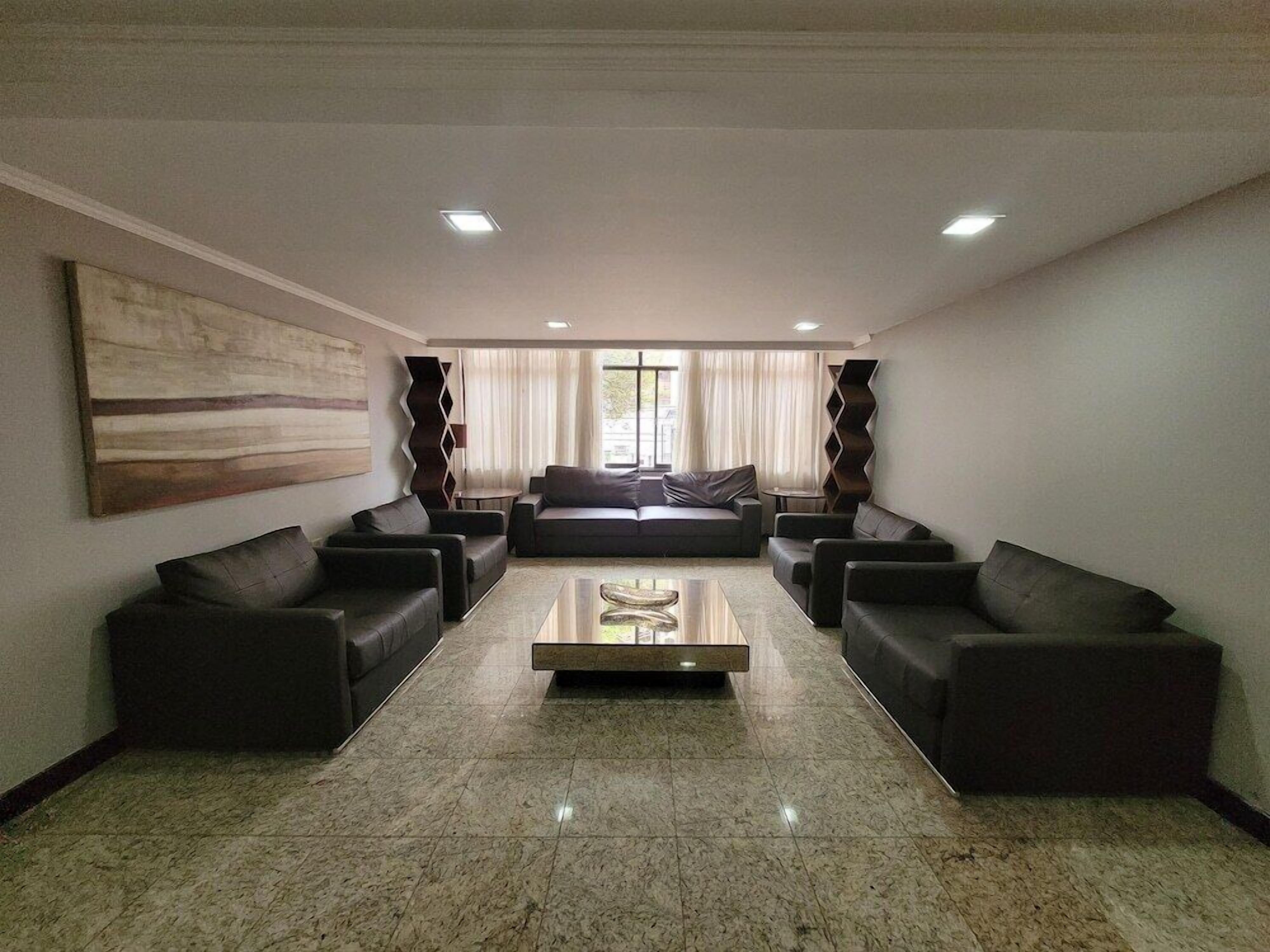 Uma sala de estar moderna com um conjunto de sofás, uma mesa de centro e uma grande pintura abstrata na parede.