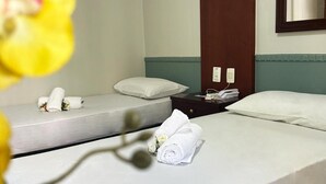 A hotel room with two beds, each with white linens and pillows, a nightstand with a lamp, and a mirror on the wall. - Hotel Alvorada Taguatinga (Taguatinga)