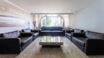 Uma sala de estar moderna com um conjunto de sofá, uma mesa de centro e uma janela grande com cortinas.