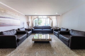 Uma sala de estar moderna com um conjunto de sofá, uma mesa de centro e uma janela grande com cortinas.